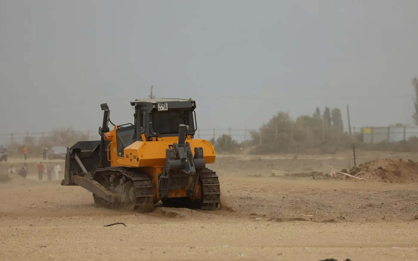 Crawler dozer cutting grade across an open dirt field